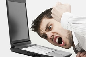 Man angrily hitting keyboard of laptop needing anger management hypnosis to control anger issues