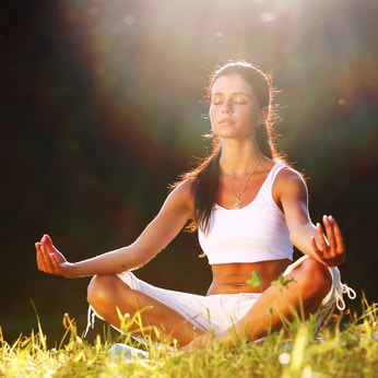 yoga woman on green grass lotus pose in sunrise light, hypnotherapy melbourne reviews